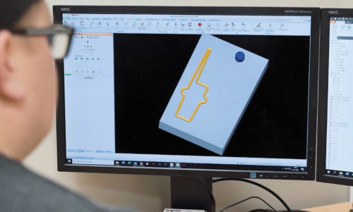 Mann jobber med uttegning foran PC skjerm